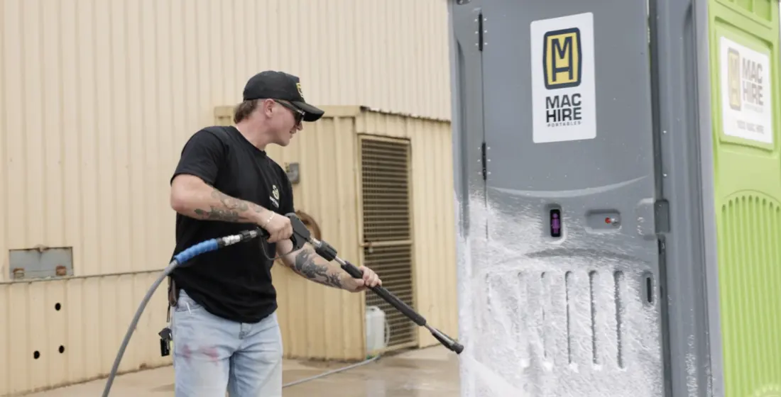 Portable toilet being pressure washed and serviced